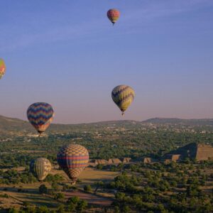 Colorful hot air balloons soaring over the ancient pyramids of Teotihuacan, Mexico.